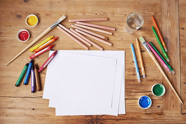 Blank paper with painting supplies and pencils on a wooden table Blank paper with painting supplies and pencils on a wooden table
